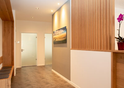 Heller, moderner Wartebereich einer Arztpraxis mit Holzelementen und Orchidee.